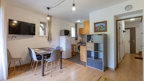 Un espace de vie compact comprenant un coin repas, une kitchenette et une petite salle de bain.