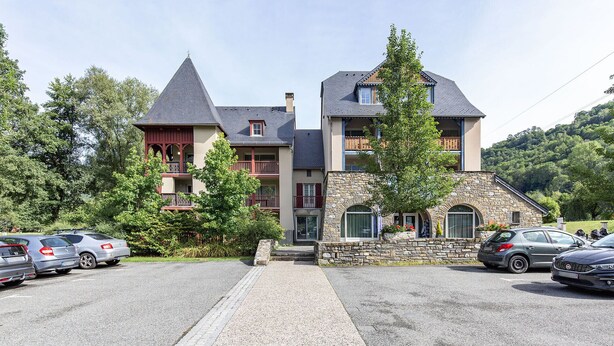 Un immeuble à plusieurs étages, doté d’une façade en pierre et d’un toit à forte pente.