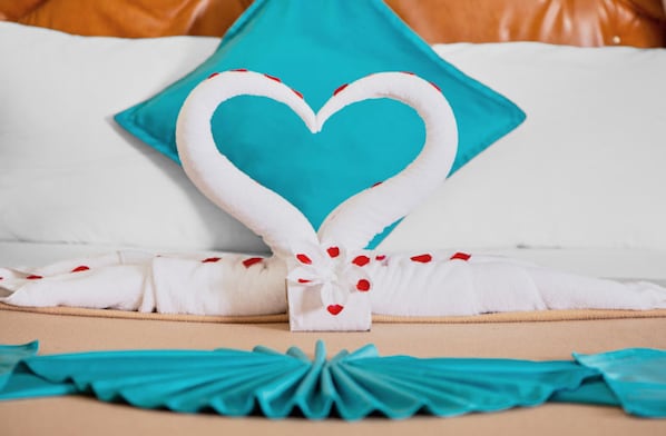 A bed with a heart-shaped towel arrangement, a teal pillow, and a teal ribbon. - Mariners Court Hotel Cebu (Cebu City)