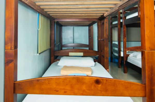 Una habitación estrecha con una cama de madera y literas.