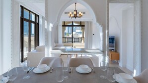 Un comedor con una mesa dispuesta para seis personas, una araña y vistas de la ciudad a través de amplias ventanas.