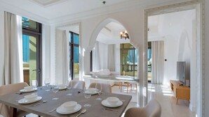 Un comedor amplio con una gran mesa dispuesta para una comida, un televisor y un balcón con vistas.