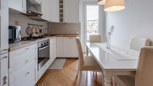 A modern kitchen with white cabinets, a stove, and a dining area with a table and chairs.