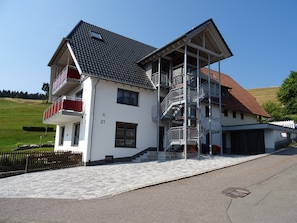 Ein zweistöckiges Haus mit Balkon, Treppe und der Hausnummer 21 an der Wand.