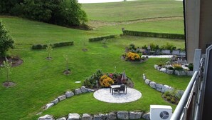 A well-maintained garden with a patio area, stone edging, and various plants. - Apartment 'Beerewieble' with Shared Garden, Balcony and Wi-Fi (Unterkirnach)