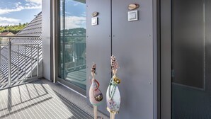 A modern building with a balcony, a glass door, and two decorative figures. - Apartment 'Beerewieble' with Shared Garden, Balcony and Wi-Fi (Unterkirnach)
