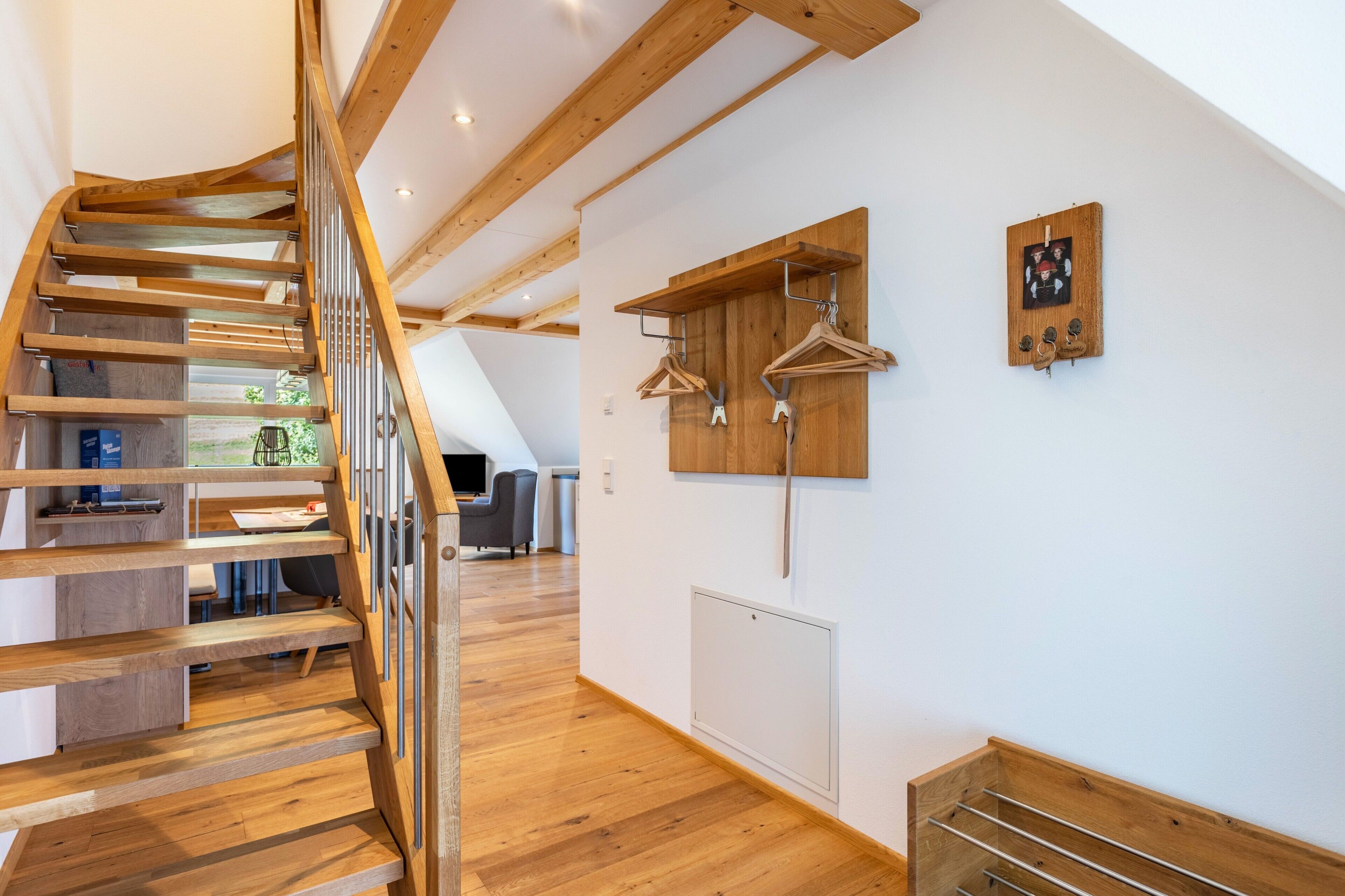 Un interior moderno con una escalera de madera, un tendedero de pared y un radiador.
