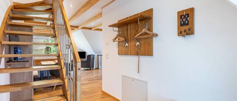 Un interior moderno con una escalera de madera, un tendedero de pared y un radiador.