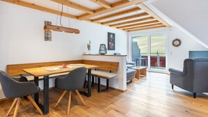 A modern interior with a wooden dining table, benches, and a grey sofa. - Apartment 'Beerewieble' with Shared Garden, Balcony and Wi-Fi (Unterkirnach)