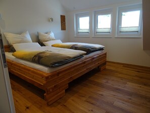 A bedroom with a wooden bed, white walls, and three windows.