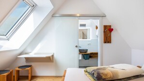 A bedroom with a skylight, a bed, a wooden bench, and a small table. - Apartment 'Beerewieble' with Shared Garden, Balcony and Wi-Fi (Unterkirnach)