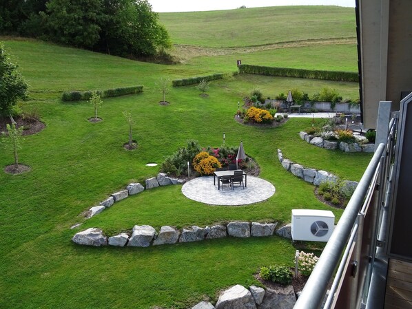 A well-maintained garden with a patio area, stone edging, and various plants.
