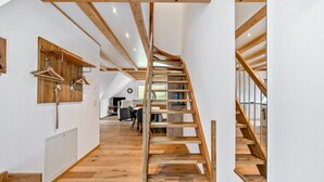 Un intérieur moderne avec un escalier en bois, des murs blancs et une vue sur un espace de vie agrémenté d’une cheminée.