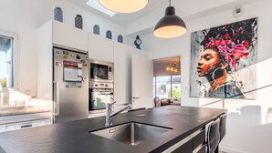 Een moderne keuken met een centraal eiland, roestvrijstalen apparatuur en een groot raam.
