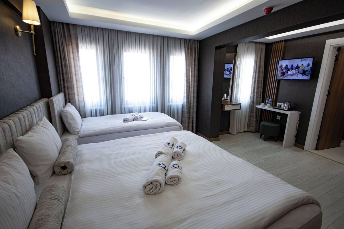 A hotel room with two beds, a TV, a small desk, and a bathroom.