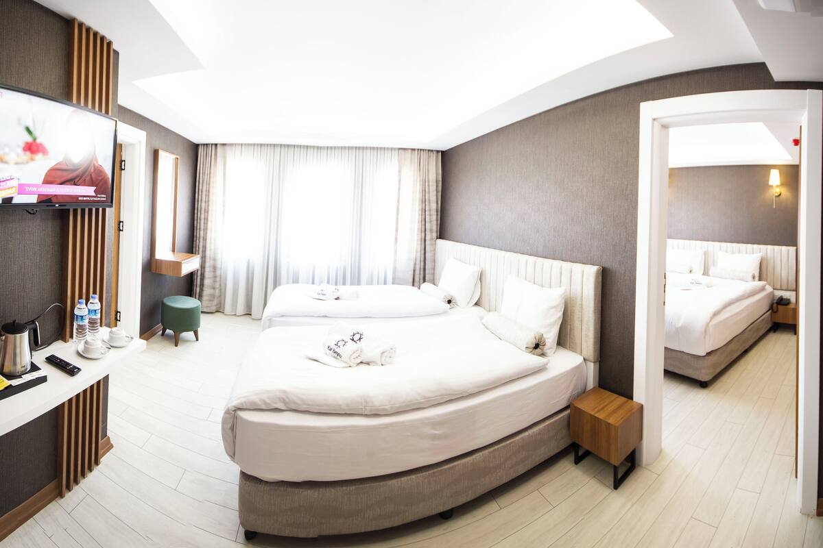 A modern hotel room with a large bed, a desk with a computer, and a mirror.