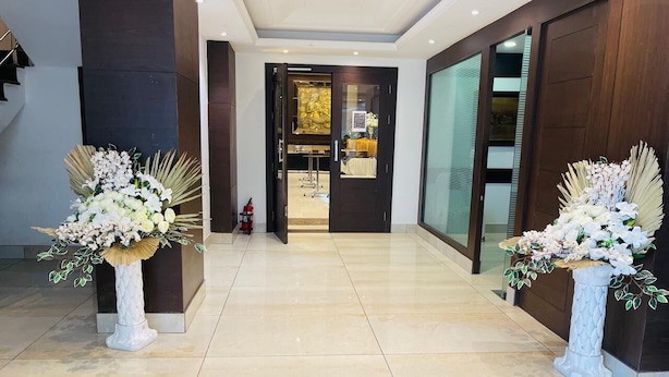 A modern hotel lobby with a marble floor, two large white vases with flowers, and a view into the room area. - Hotel A9 Resorts (Raikot)