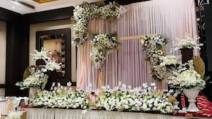 A stage with floral arrangements and draped curtains, likely set up for a formal event. - Hotel A9 Resorts (Raikot)