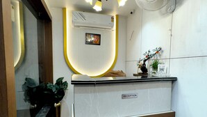A reception desk with a modern design, a ceiling fan, and a wall-mounted air conditioner. - Ace Stayz (Varanasi)