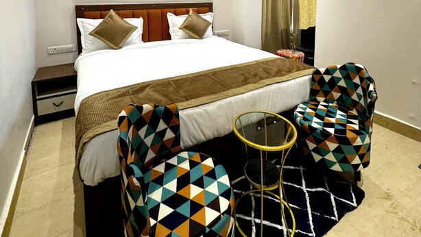 A hotel room with a bed, a ceiling fan, a wall-mounted air conditioner, and a decorative painting. - Ace Stayz (Varanasi)