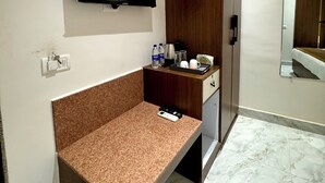A modern bathroom with a flat-screen TV mounted on the wall, a wooden vanity with a countertop, and a mirror. - Ace Stayz (Varanasi)