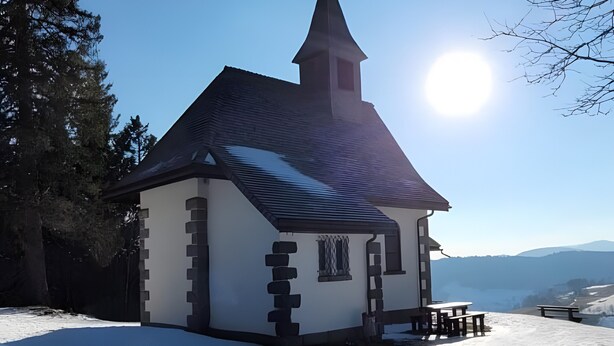 A small church with a steeple, surrounded by snow and trees. - Gästehaus Weilerhof – Very Quiet and Sunny Location (Todtnauberg)