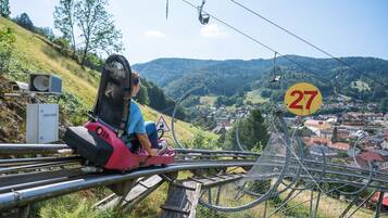 A person on a chairlift with a scenic view of a town and hills in the background.