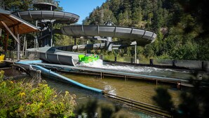 A water ride with a green boat, wooden structures, and a forested hillside. - Gästehaus Weilerhof – Very Quiet and Sunny Location (Todtnauberg)