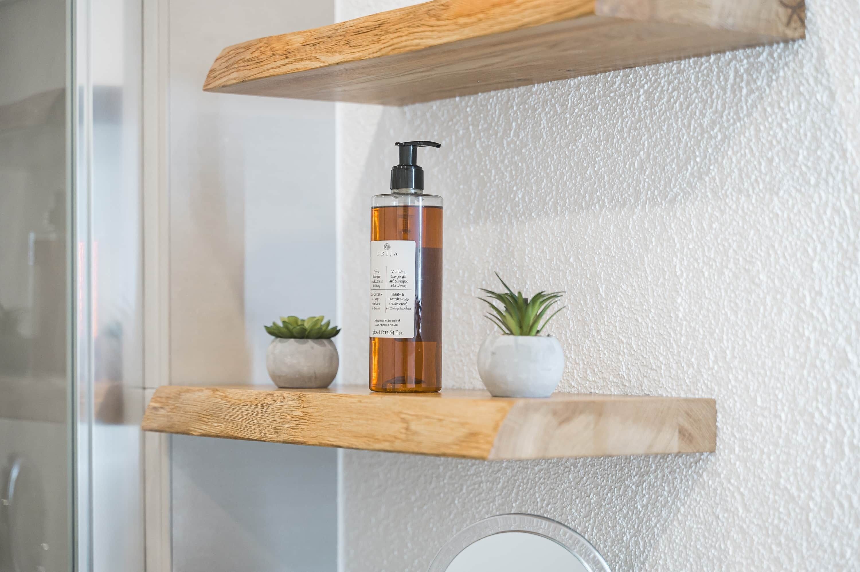 Een badkamerschaar met een shampoo, twee kleine planten in potten, en een houten plank.