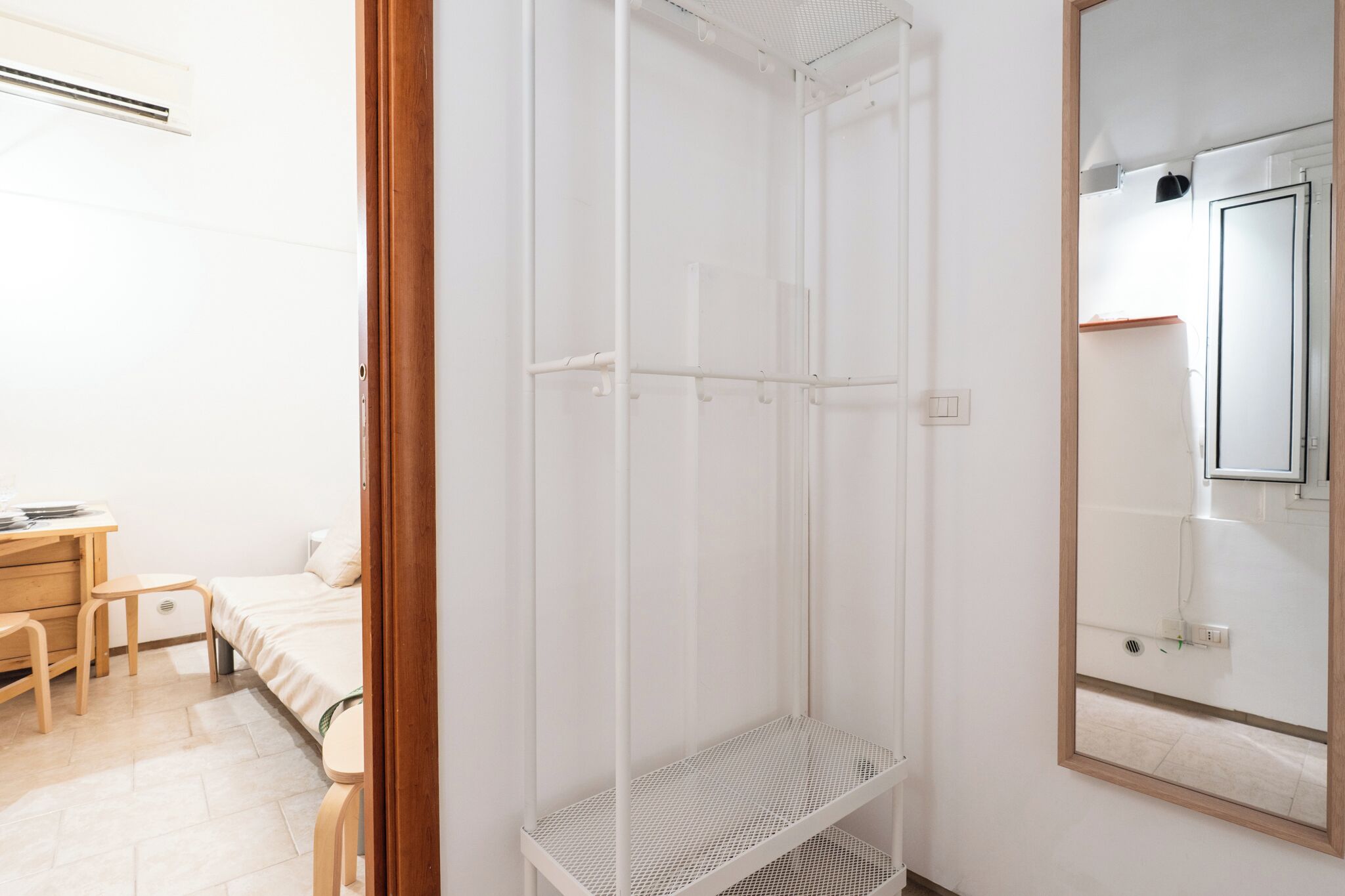 A room with a bed, a desk, a chair, a wardrobe, and a mirror.