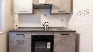 A modern kitchen with a built-in oven, a kettle, and a stainless steel range hood. - Meta Apartment by Wonderful Italy  (Bari)