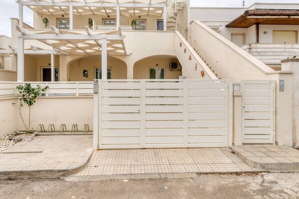 A gated entrance with a staircase leading to a building with a white facade and multiple balconies.