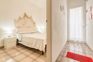 A bedroom with a bed, bedside table, and a red doormat.