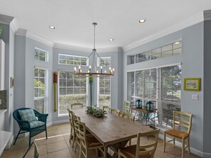 A dining room with a wooden table and chairs, large windows, and a chandelier. - Tivoli Beach Villa w/ Golf Cart in Sandestin Resort (Miramar Beach)