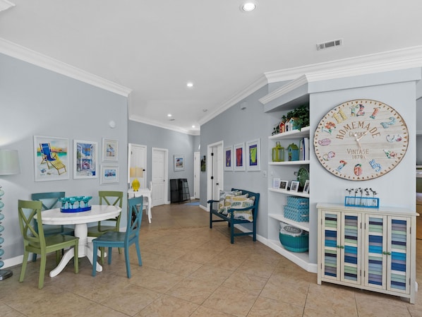 A dining area with a round table, chairs, and a wall clock.