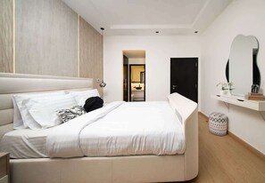 Una camera da letto moderna con un letto grande, un comodino, uno specchio e un piccolo sgabello.