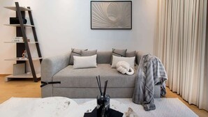 A modern living room with a grey sofa, a black bookshelf, and a framed artwork on the wall. - Dubai Marina Apt w/ Pool, Gym & Balcony Views (Dubai)