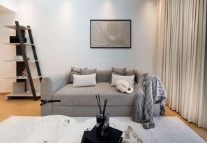 Un soggiorno moderno con un divano grigio, una libreria nera e un quadro appeso al muro.