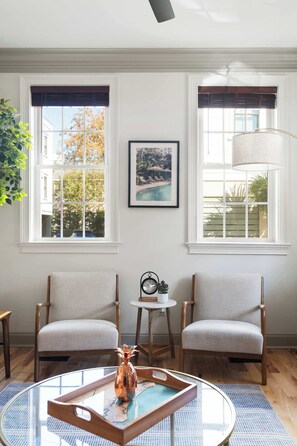 Una habitación con dos sillas, una mesa redonda y una ventana que ofrece vistas a edificios y árboles.