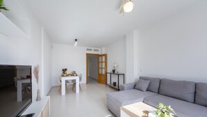 Una sala de estar moderna con un sofá gris, una mesa de centro de madera y un televisor sobre un mueble.