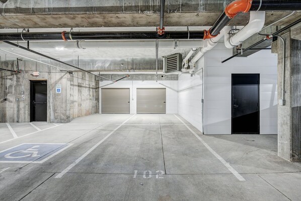 Un parking souterrain aux murs en béton, doté de deux portes de garage fermées et d’une place de stationnement réservée aux personnes handicapées.