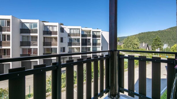 A modern building with multiple balconies and a view of a green landscape.
