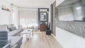 A modern living room with a grey sofa, a white coffee table, and a TV mounted on the wall. - Your Large Family Apartment in Zaragoza (Zaragoza)