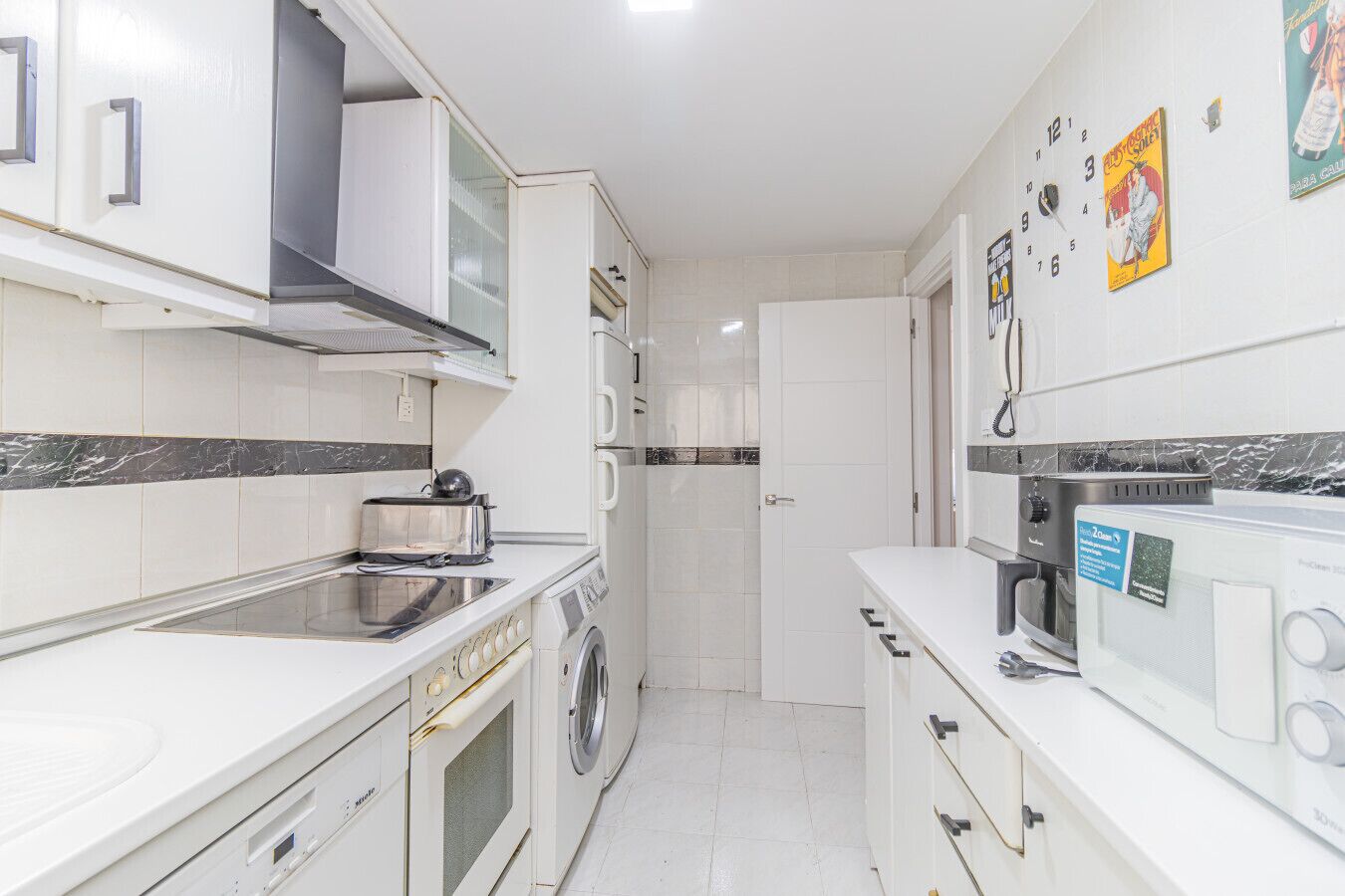 A modern kitchen with a built-in oven, microwave, and a washing machine.