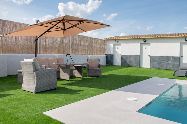 Un jardin avec une piscine, du mobilier d’extérieur et une clôture en bois.