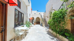 A narrow alleyway with a table and chairs set up for outdoor dining, a staircase leading to an upper level, and a building with a stone facade.