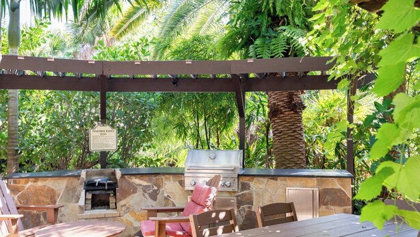 Un patio al aire libre con pared de piedra, una parrilla y mobiliario de madera.