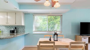 Una cocina moderna con un amplio ventanal, sillas de madera y una mesa de comedor.