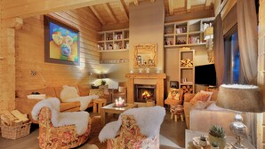 A cozy log cabin interior with a fireplace, wooden walls, and a comfortable seating area with plush chairs and sofas. - Ready for renovation! | 4-minute walk to the ski lift | 10-minute walk to the wellness center/spa (Les Collons 1800m)