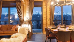 A cozy wooden interior with a dining area, a sofa with a furry throw, and large windows overlooking a snowy mountain. - Ready for renovation! | 4-minute walk to the ski lift | 10-minute walk to the wellness center/spa (Les Collons 1800m)